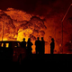 Residents look on as flames burn through bush on January 04, 2020 in Lake Tabourie, Australia.